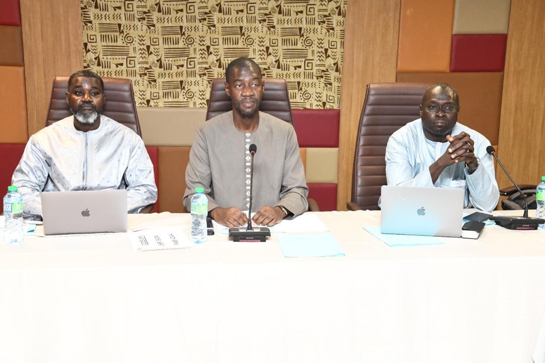 Trois participants assis derrière des micros à la table de séance